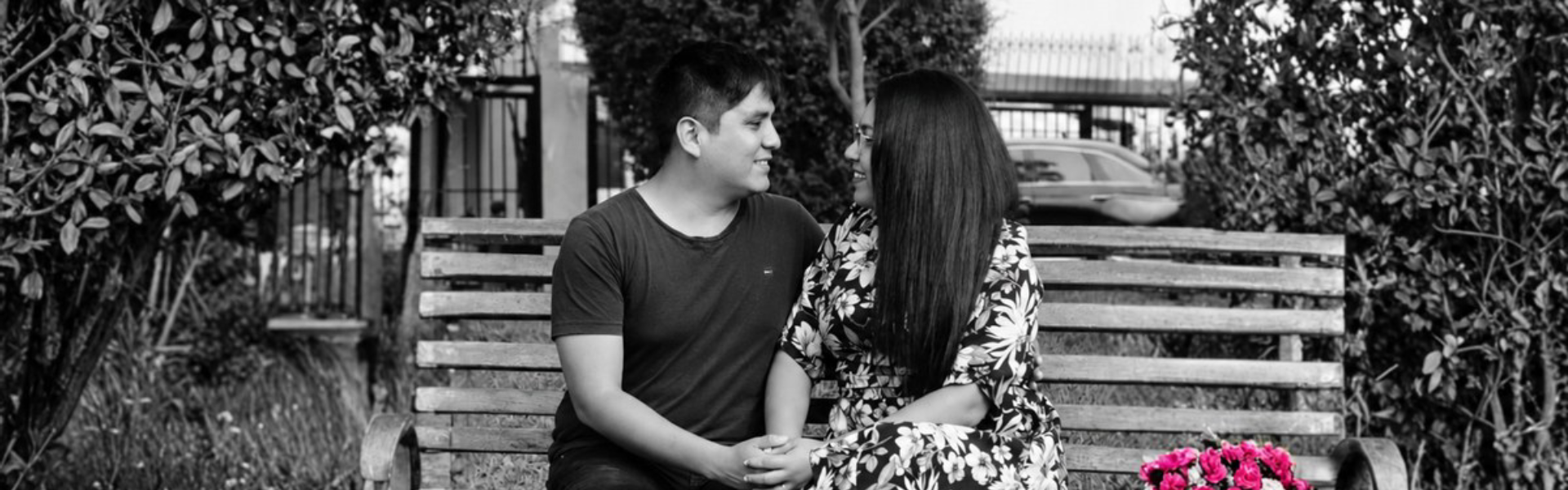 Nazarena and Robert sit on a bench, holding hands and looking at each other.